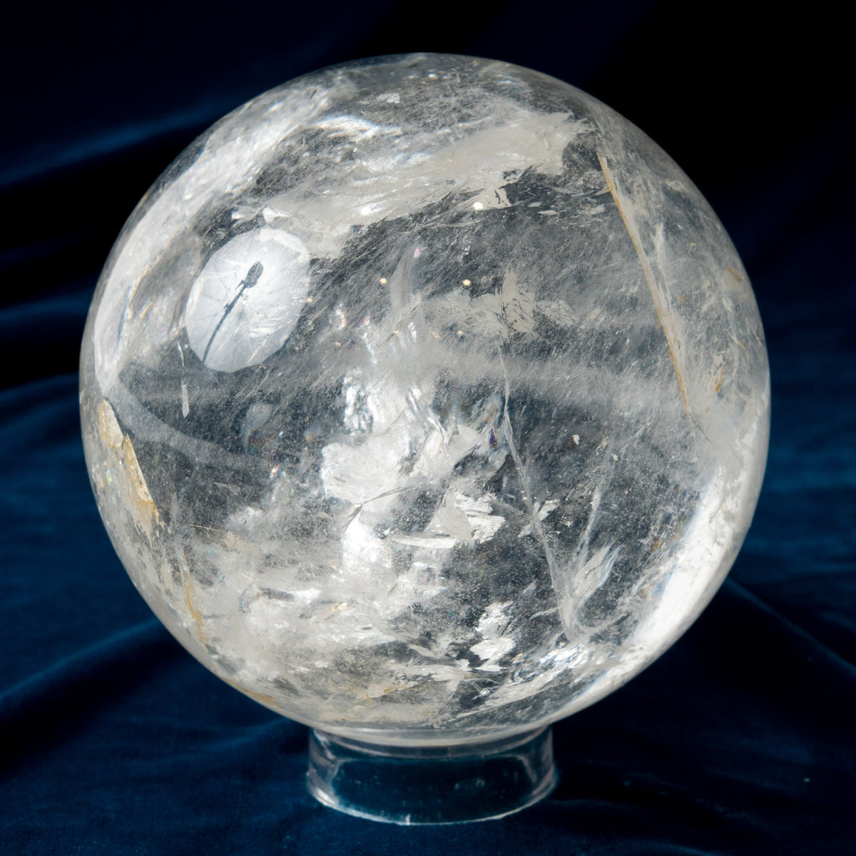Clear crystal sphere on a dark blue fabric background