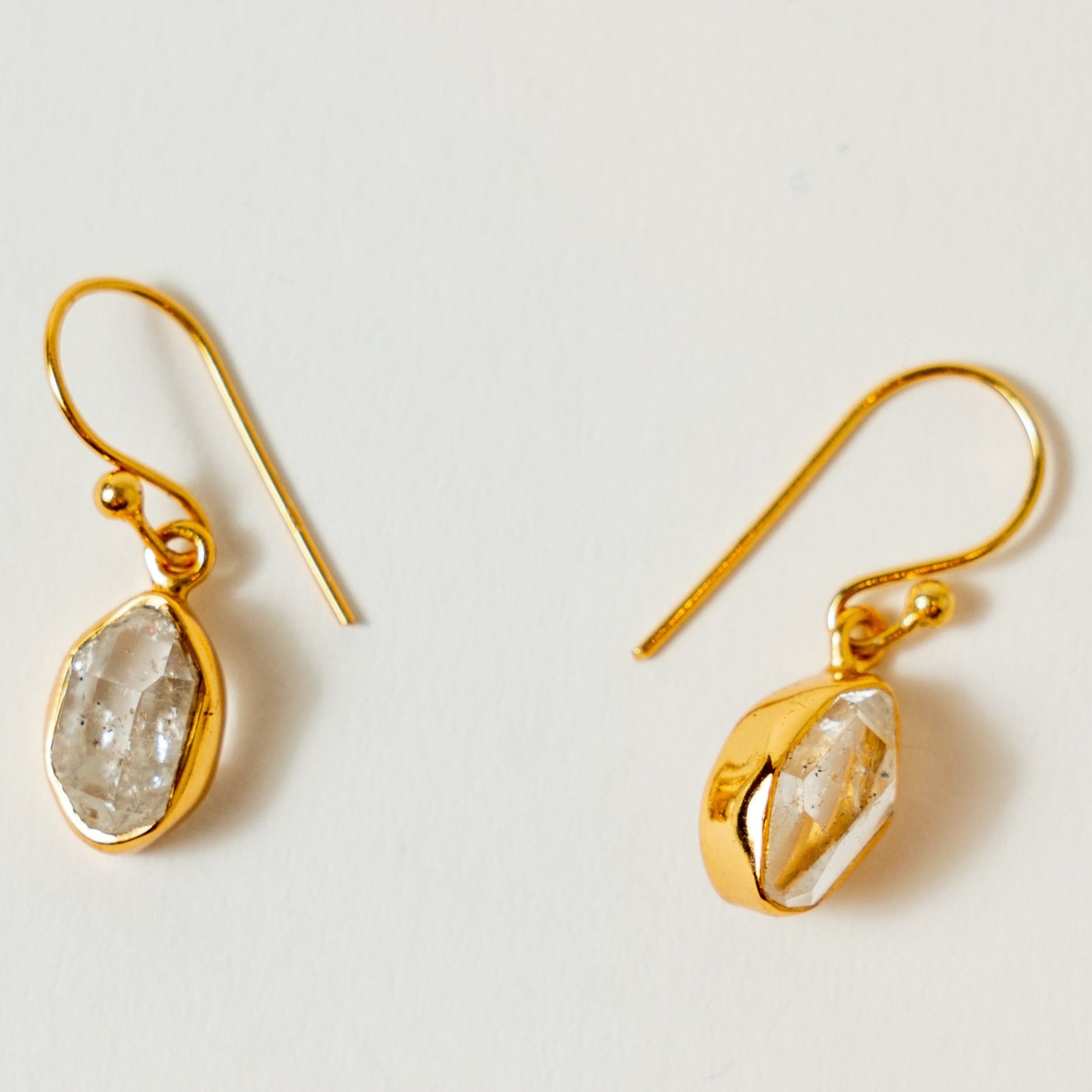 Gold herkimer earrings with natural stone drops on a light gray background
