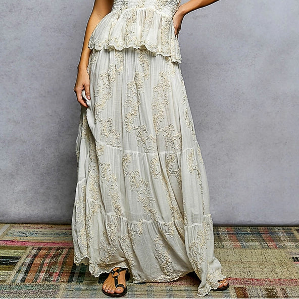 Woman wearing a long, light-colored dress against a gray background