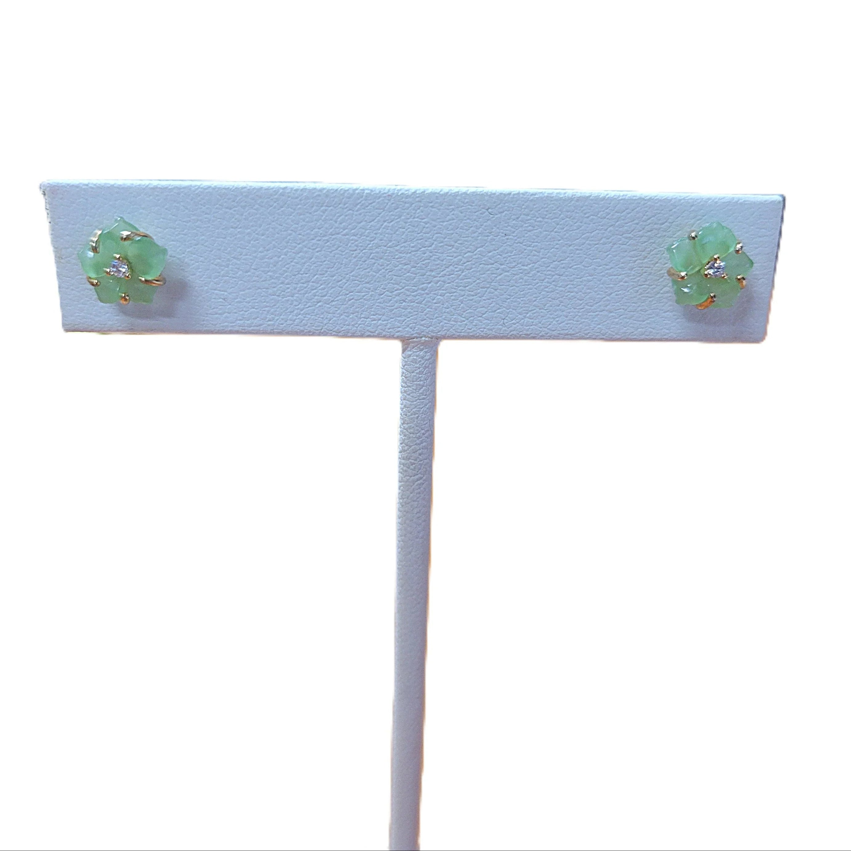 Pair of green earrings on a white earring stand with a white background