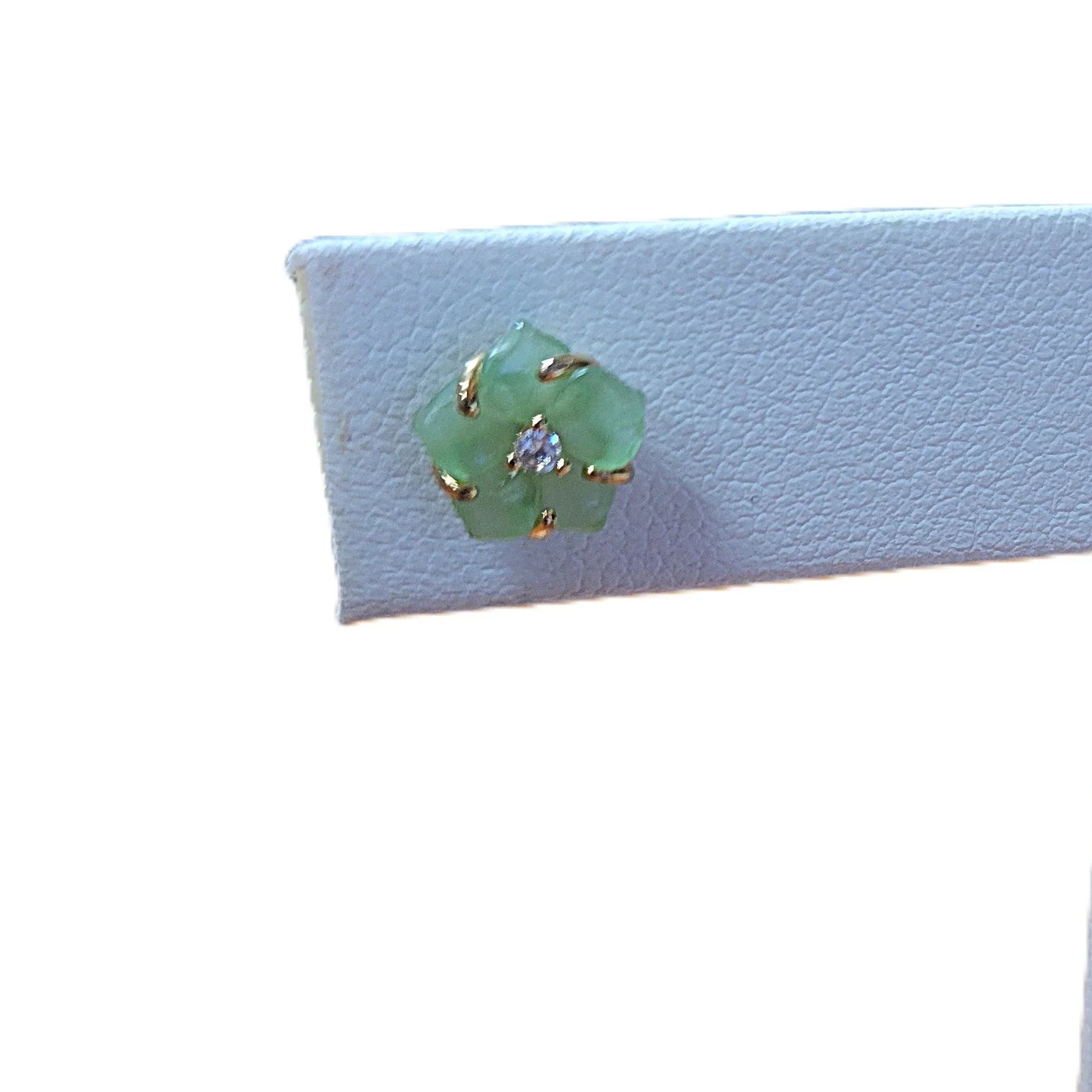 Green gemstone brooch with gold setting on a white background