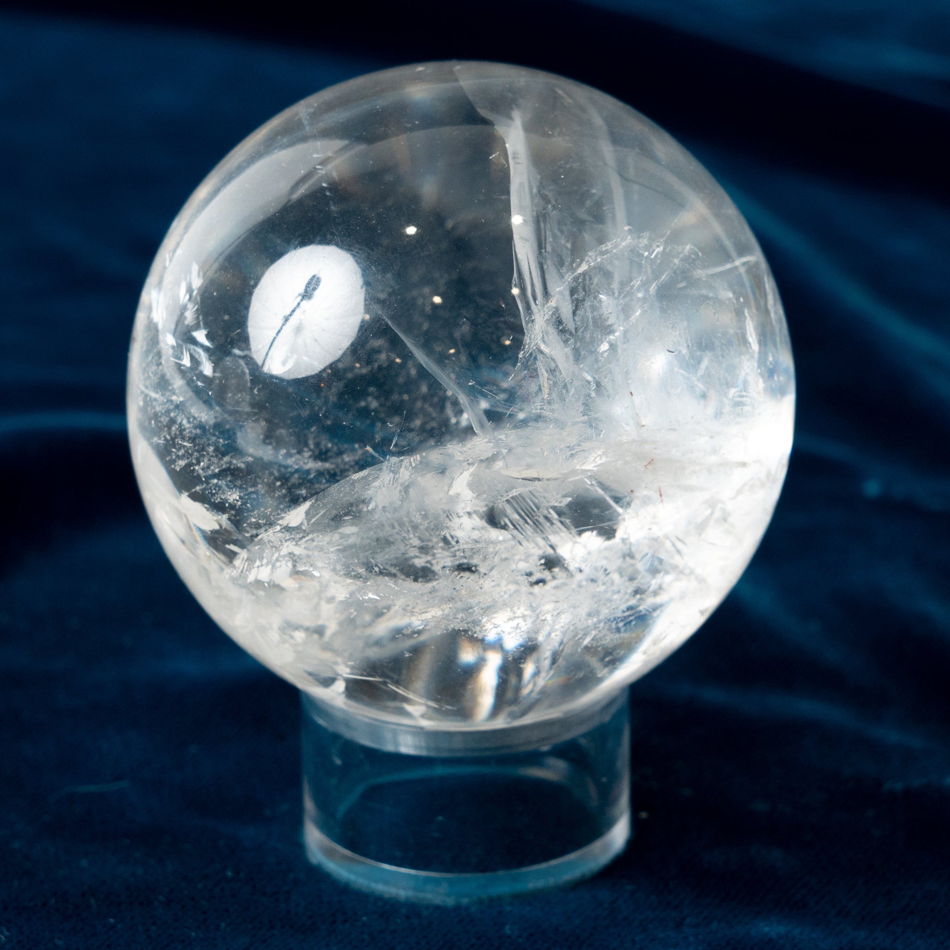 Clear crystal ball on a dark blue fabric background