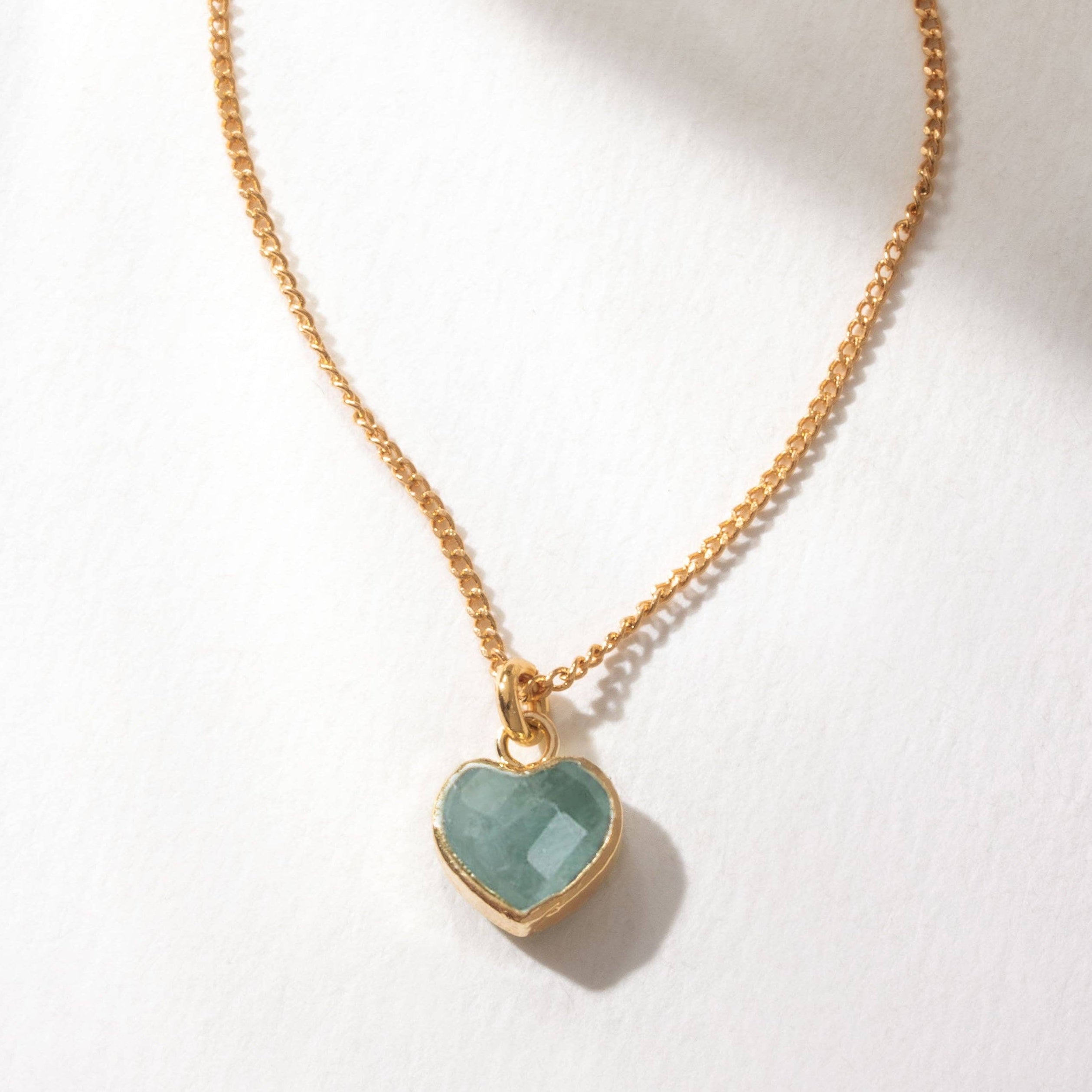 Gold necklace with a heart-shaped Aquamarine pendant on a white background