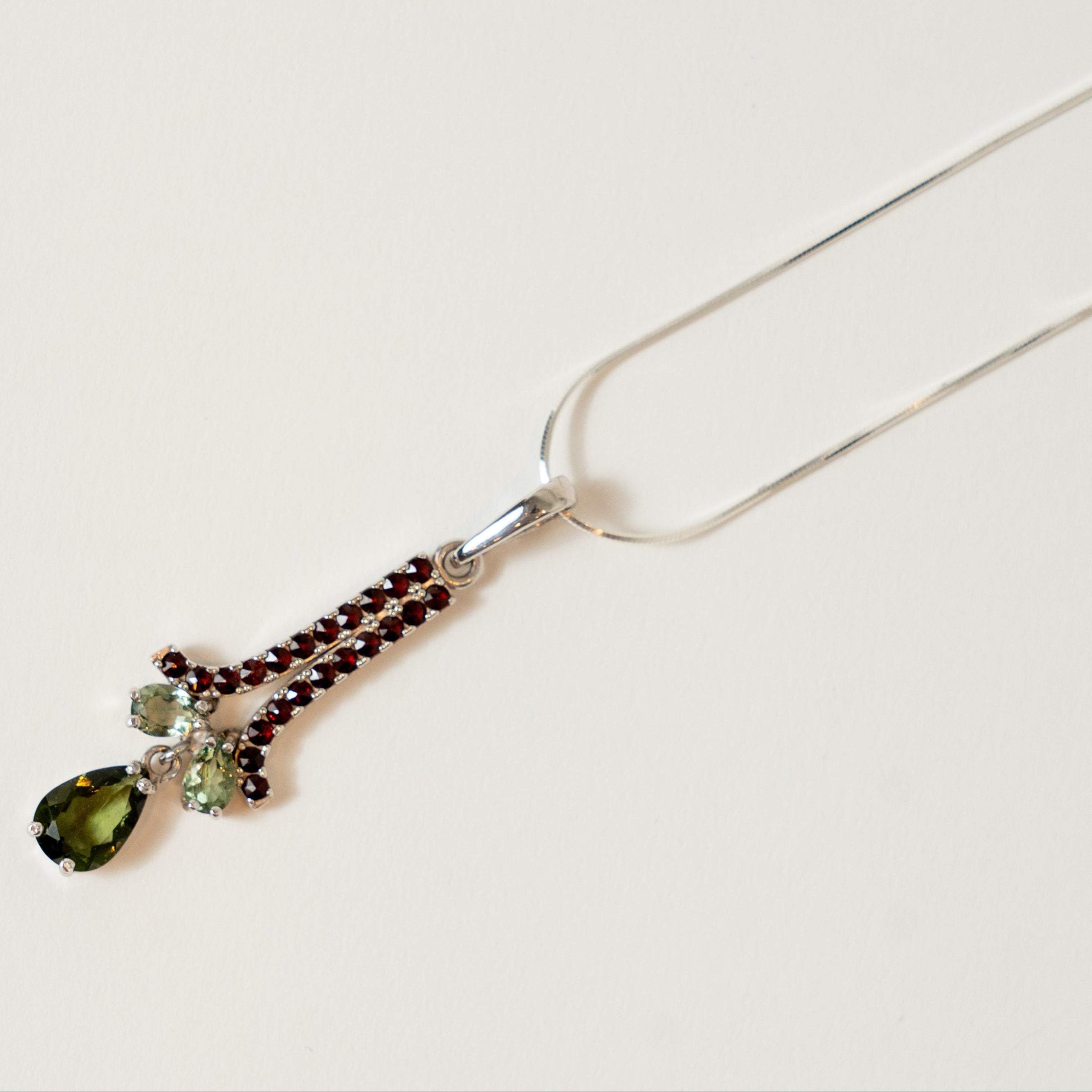 Necklace with green moldavite teardrop pendant on a white background