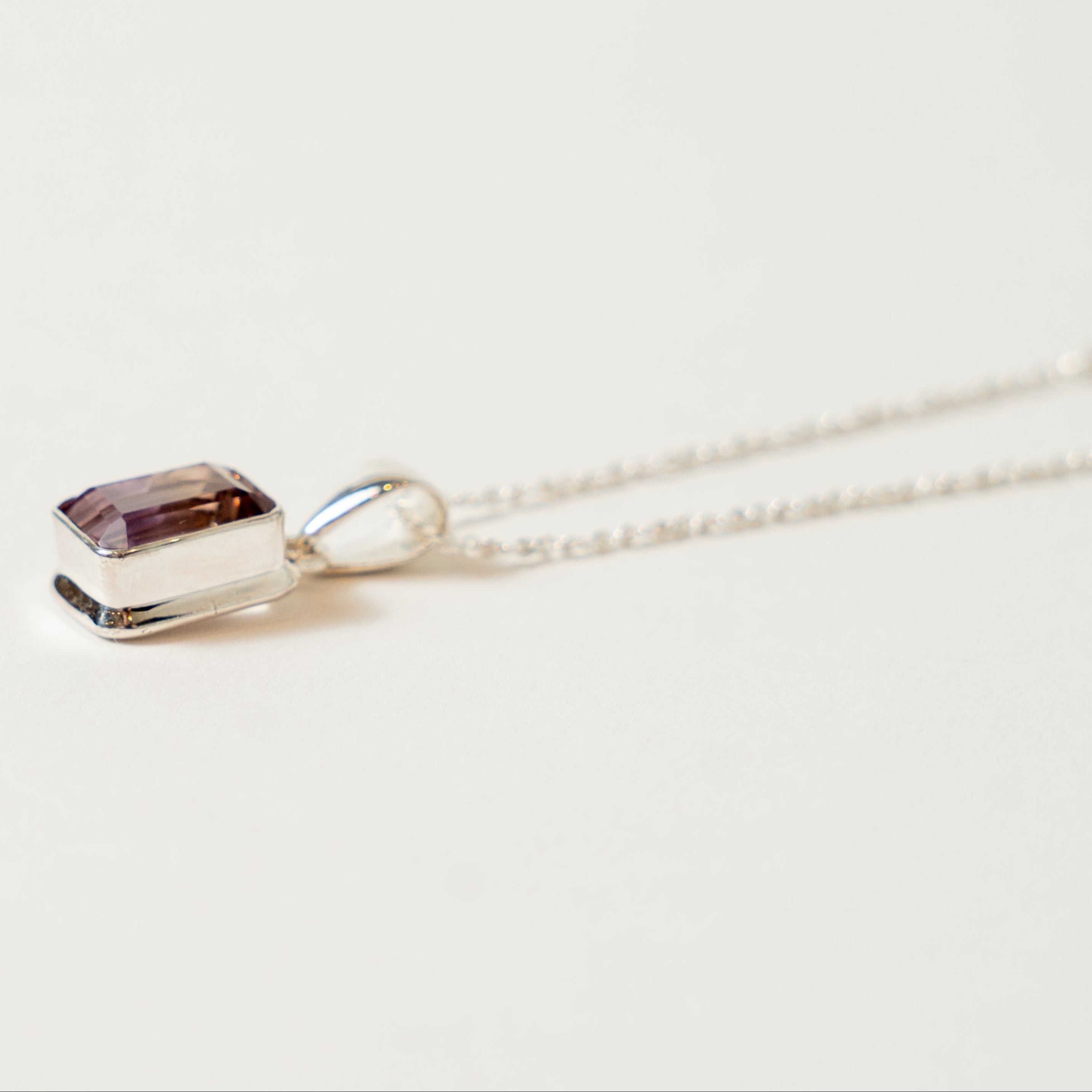 Necklace with a ametrine pendant on a light beige background