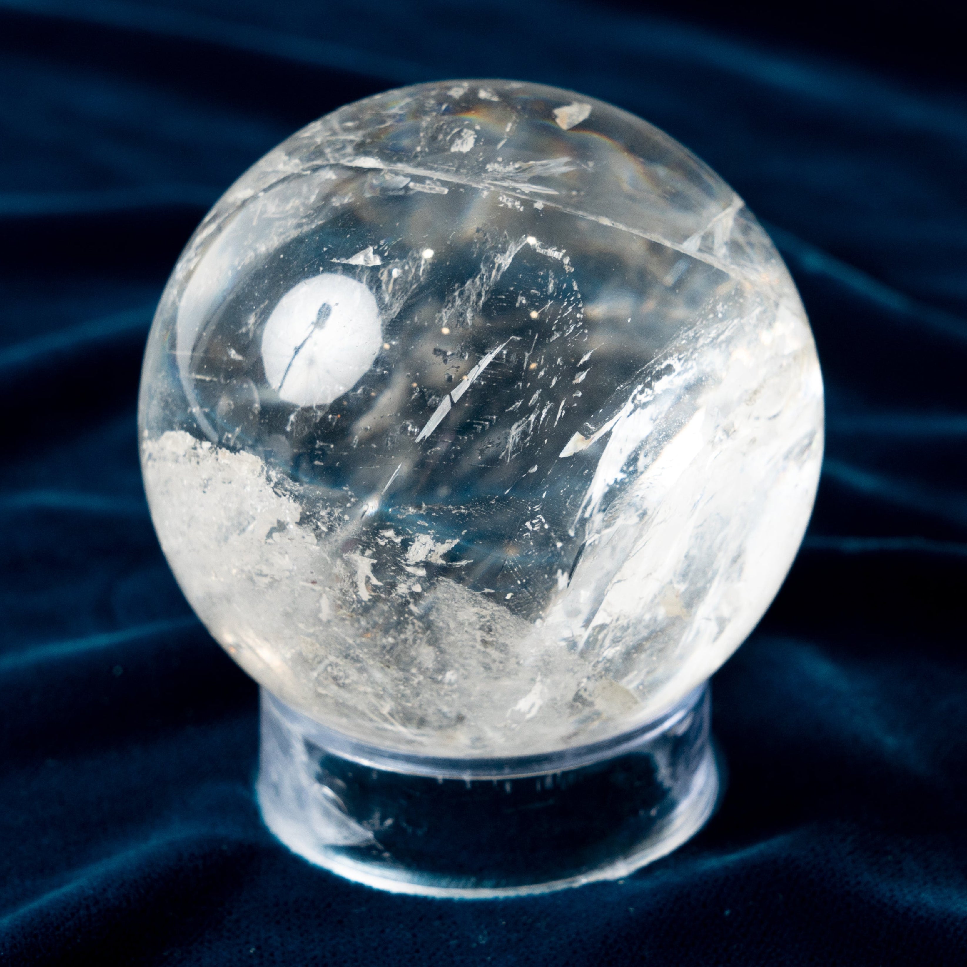 Bigger Clear crystal sphere on a dark blue fabric background