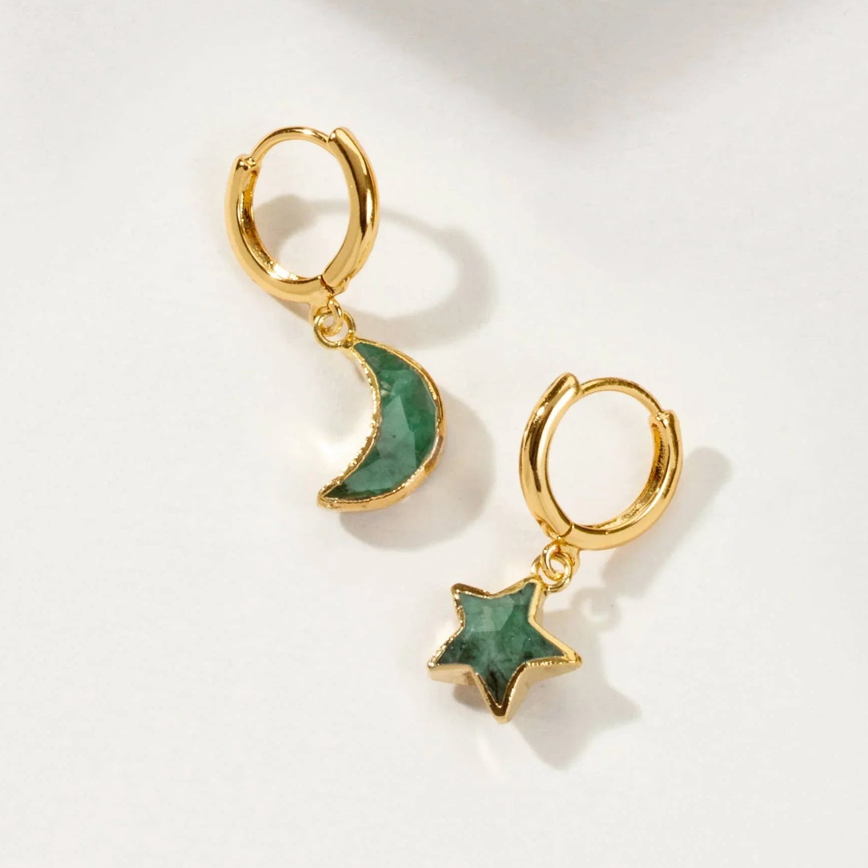 Gold hoop earrings with green stone moon and star charms on a light background