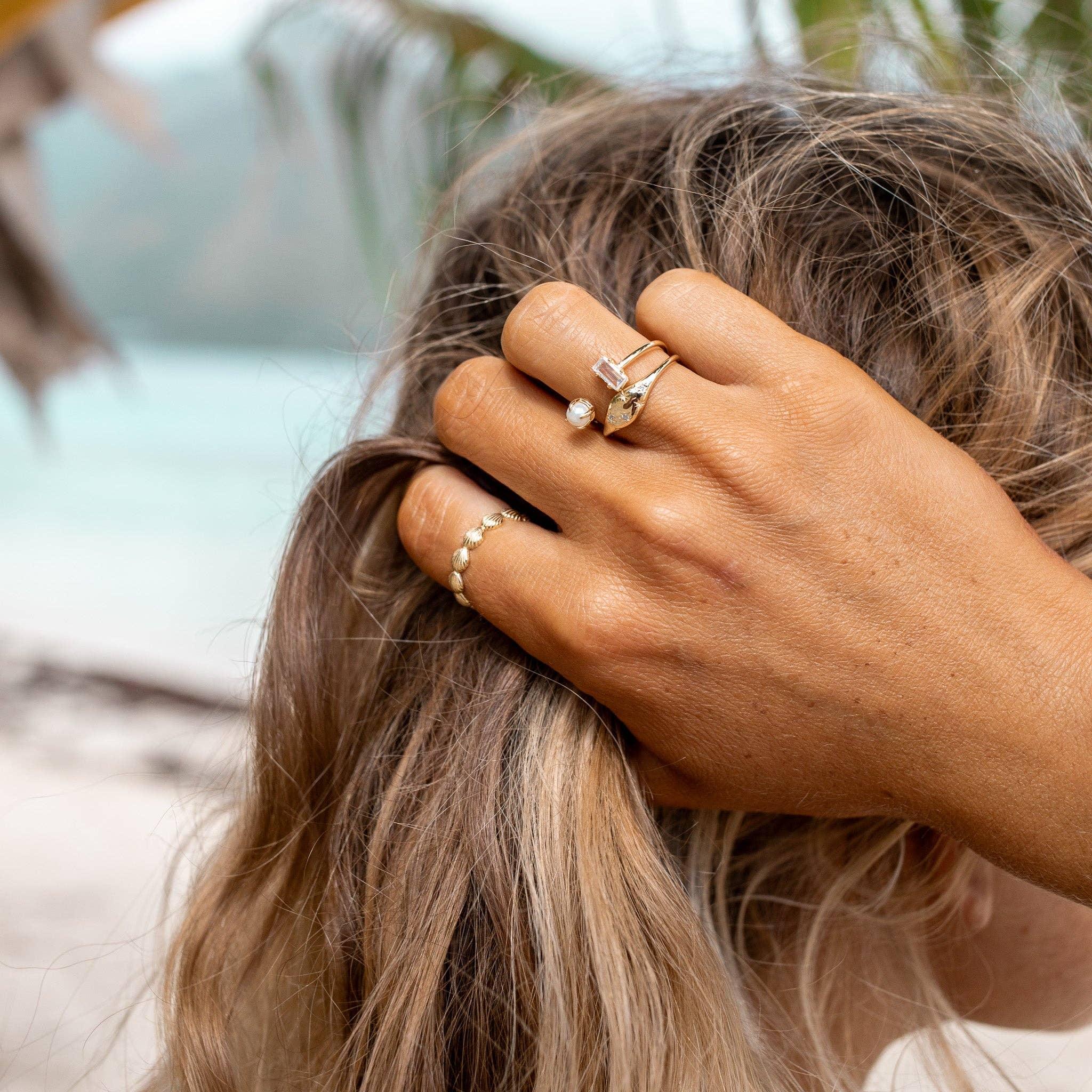Close-up of a hand with multiple rings on a blurred natural background