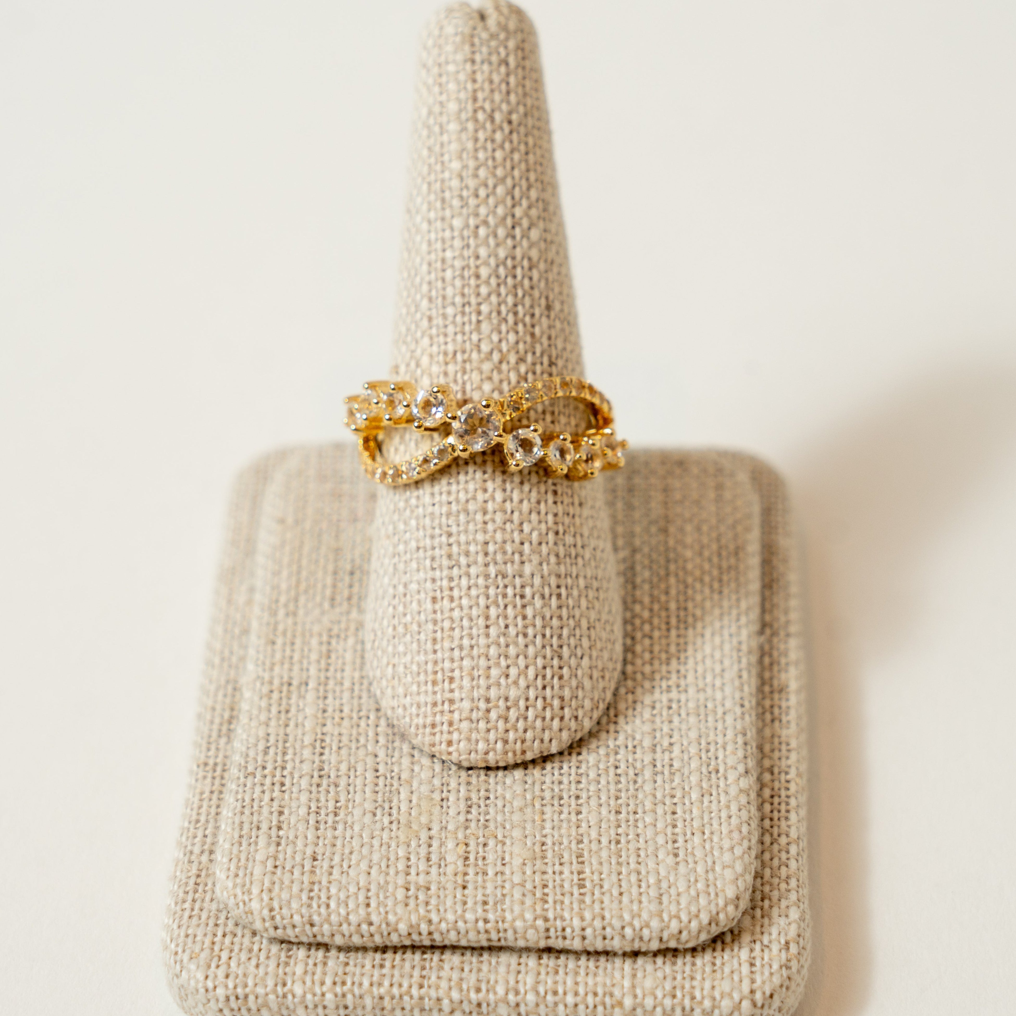Gold ring on a textured beige stand against a light background