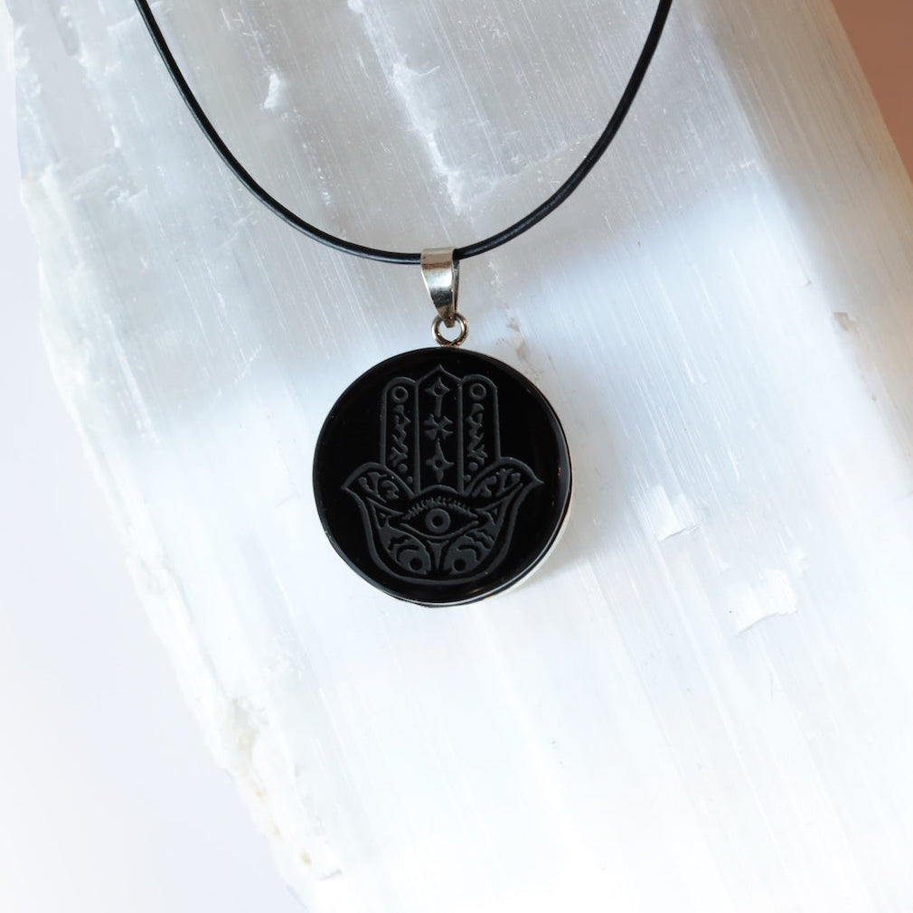Black obsidian pendant necklace on a white stone surface