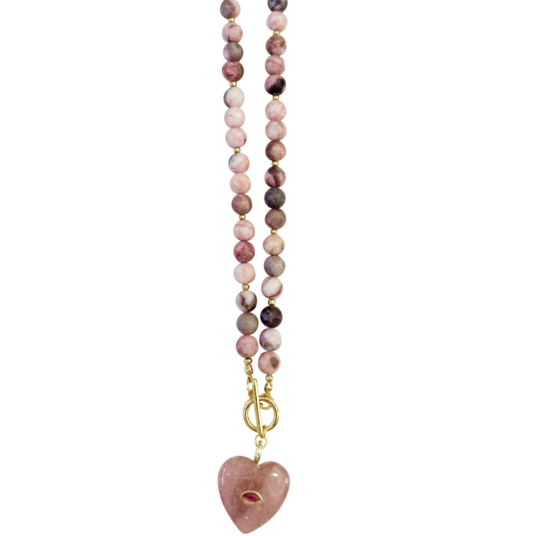 A beaded necklace featuring round pink zebra jasper stone beads with a gold-tone clasp and a polished pink heart-shaped pendant, shown against a plain white background.