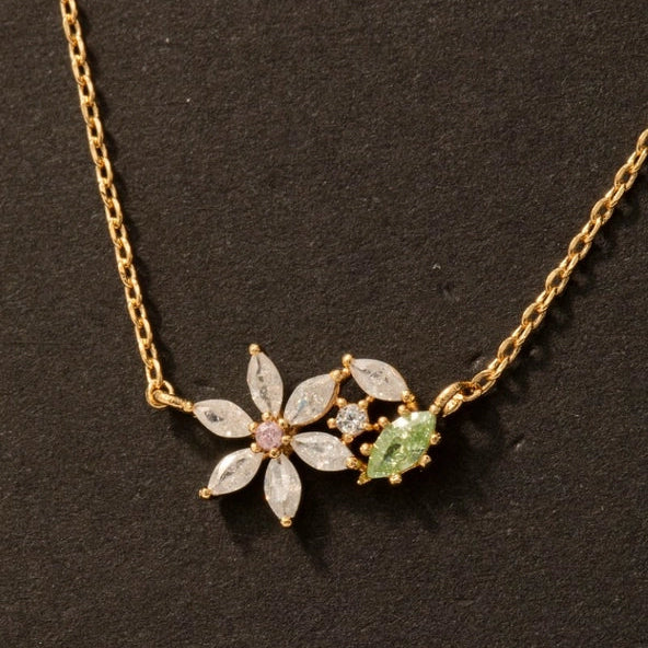 Gold necklace with floral and leaf designs on a dark background
