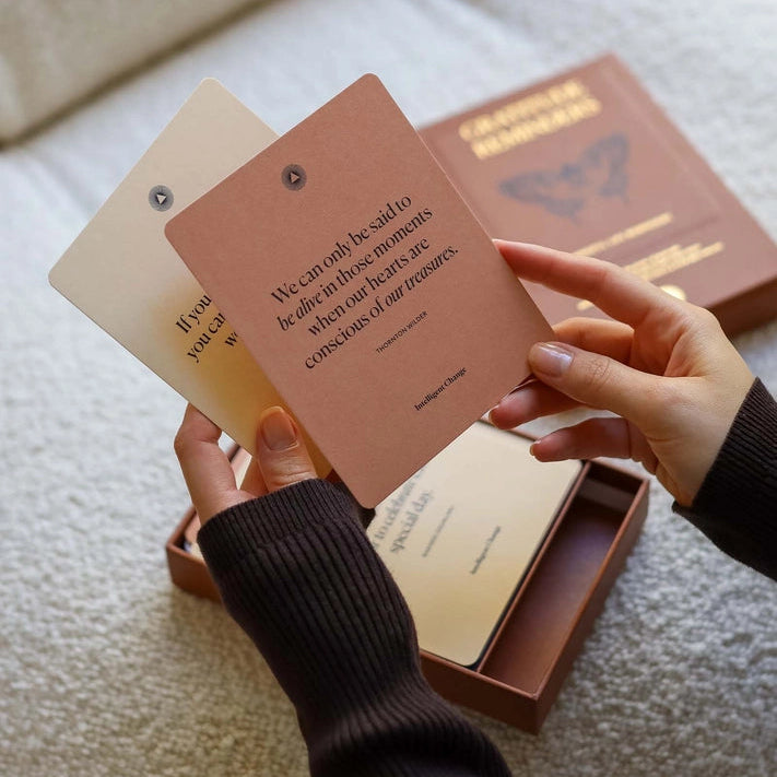 Person holding a set of small books or notebooks with text on a light surface.