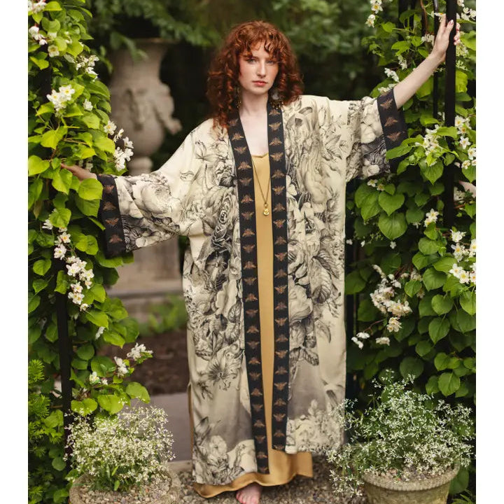 Woman in a floral dress standing among greenery and flowers