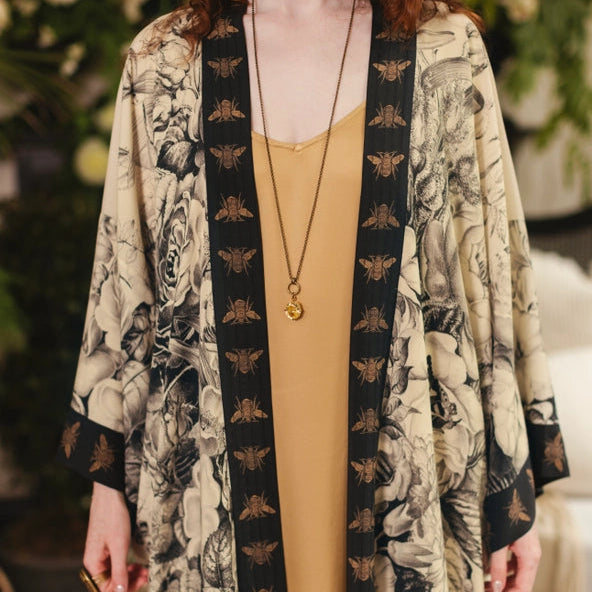 Person wearing a floral kimono over a yellow dress with a blurred floral background