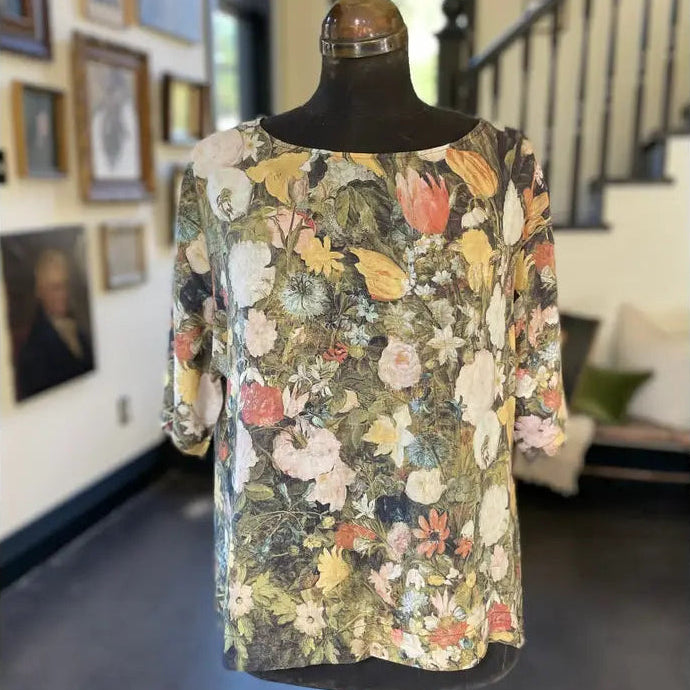 Floral dress on a mannequin in a room with framed pictures and a staircase.