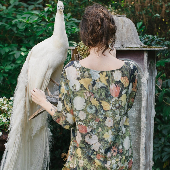 Person holding a white peacock in a garden setting