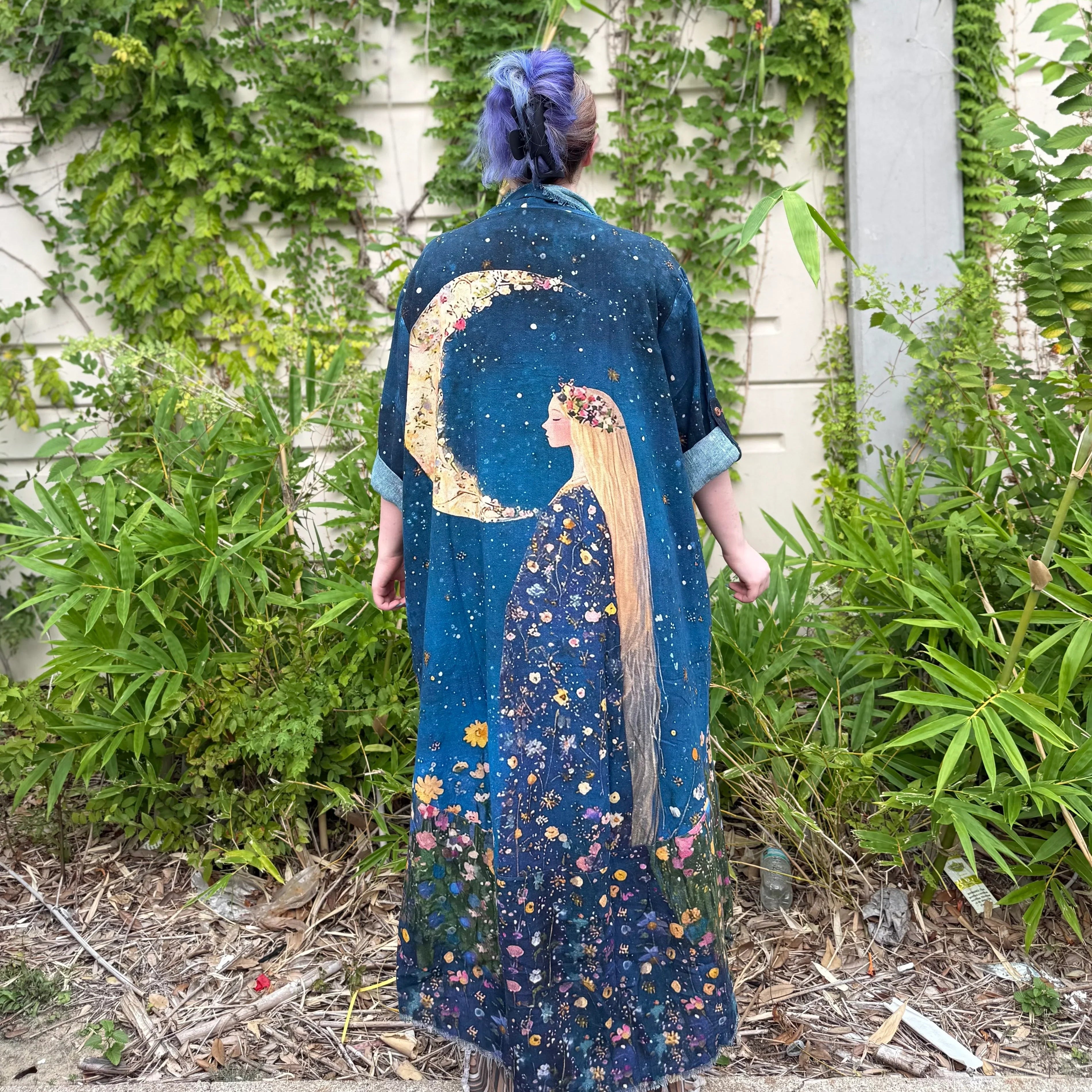 Person wearing a Teal Moon Duster with celestial design standing in front of greenery