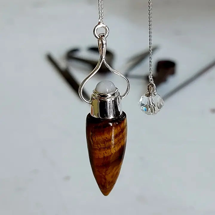 Tiger's eye pendulum with silver accents on a blurred background