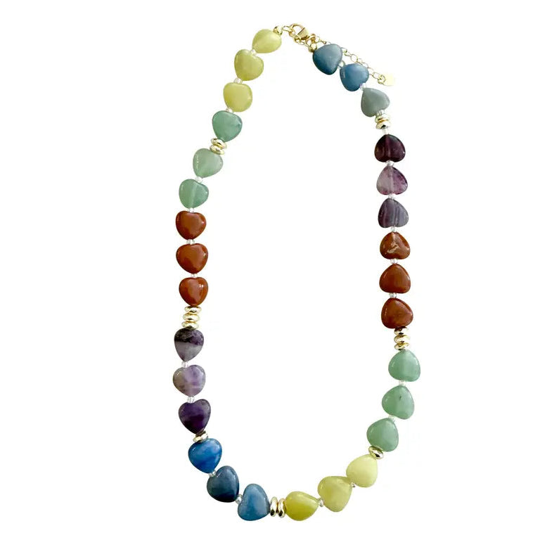 A heart-shaped gemstone beaded necklace arranged in an oval shape on a plain white background. The beads transition through multiple colors including green, blue, purple, brown, and yellow, separated by small gold spacer beads and clasp.