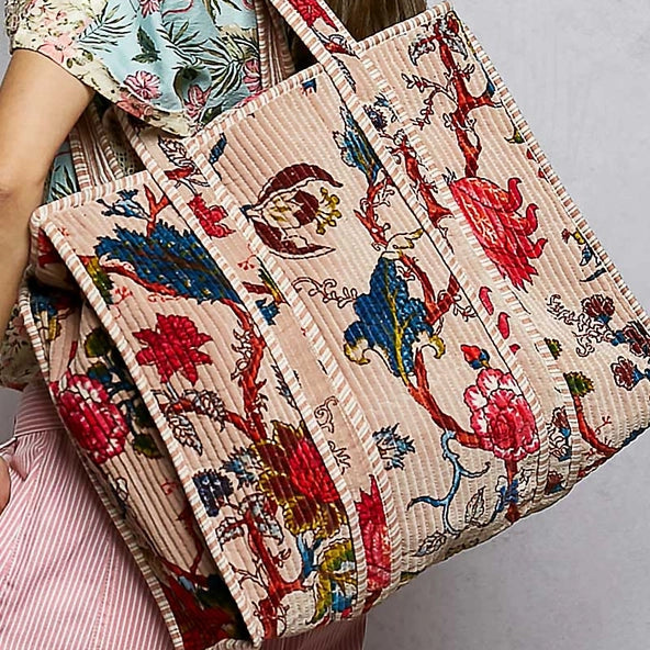 Person holding a colorful embroidered bag with intricate patterns on a plain background