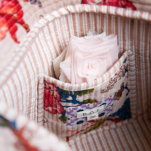 Close-up of a fabric basket with floral patterns and a white flower inside.
