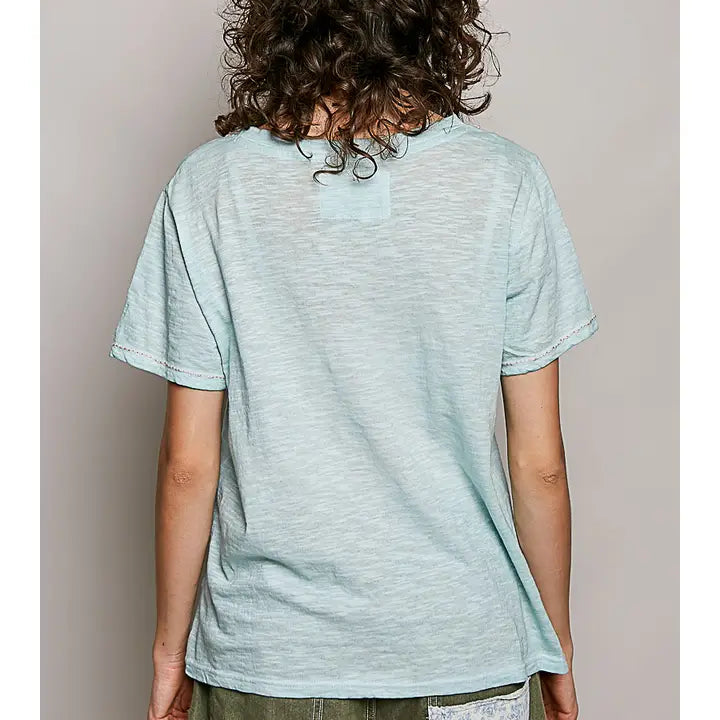 A person shown from the back wearing a light mint green short-sleeve t-shirt and olive green pants, standing against a plain light gray background.