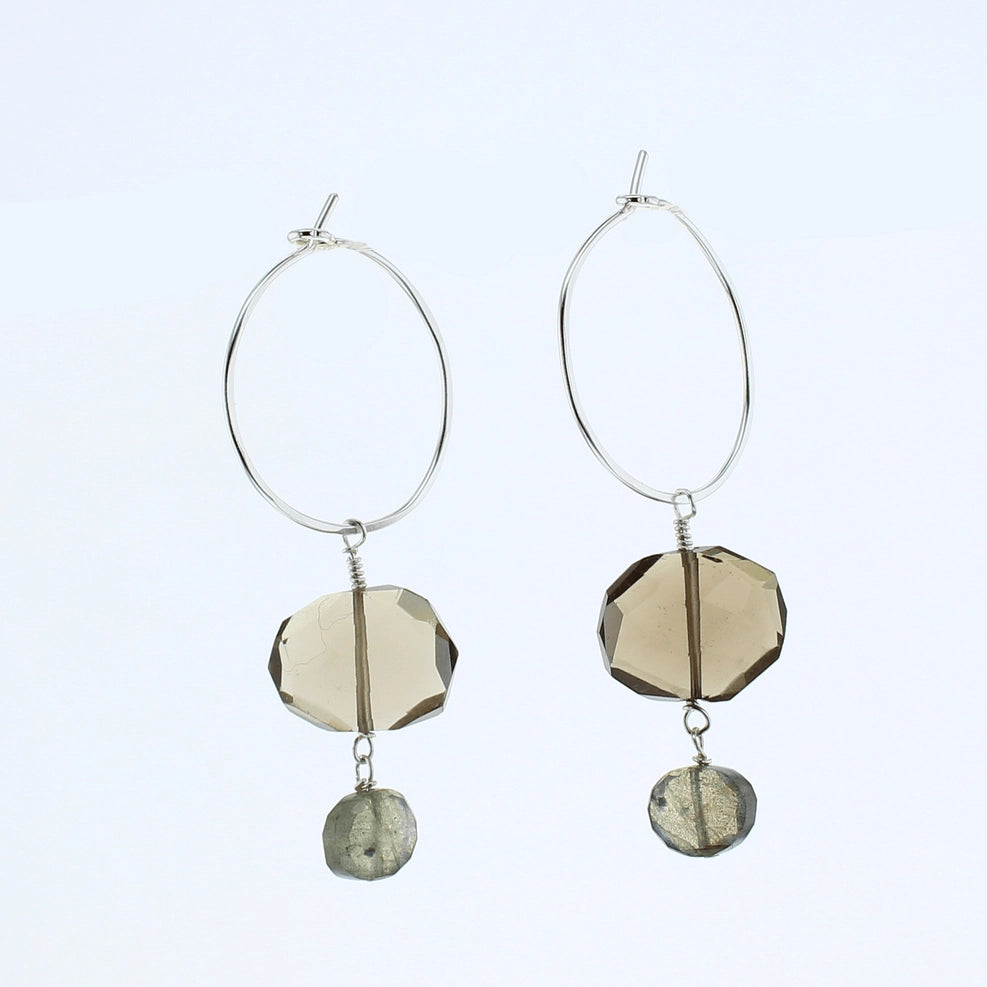 A pair of silver hoop dangle earrings featuring faceted smoky quartz beads and a small labradorite charm, shown against a plain white background.