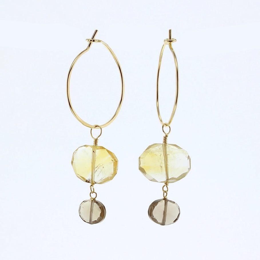 A pair of gold hoop drop earrings featuring faceted yellow citrine and smoky quartz gemstone charms, displayed against a clean white background.