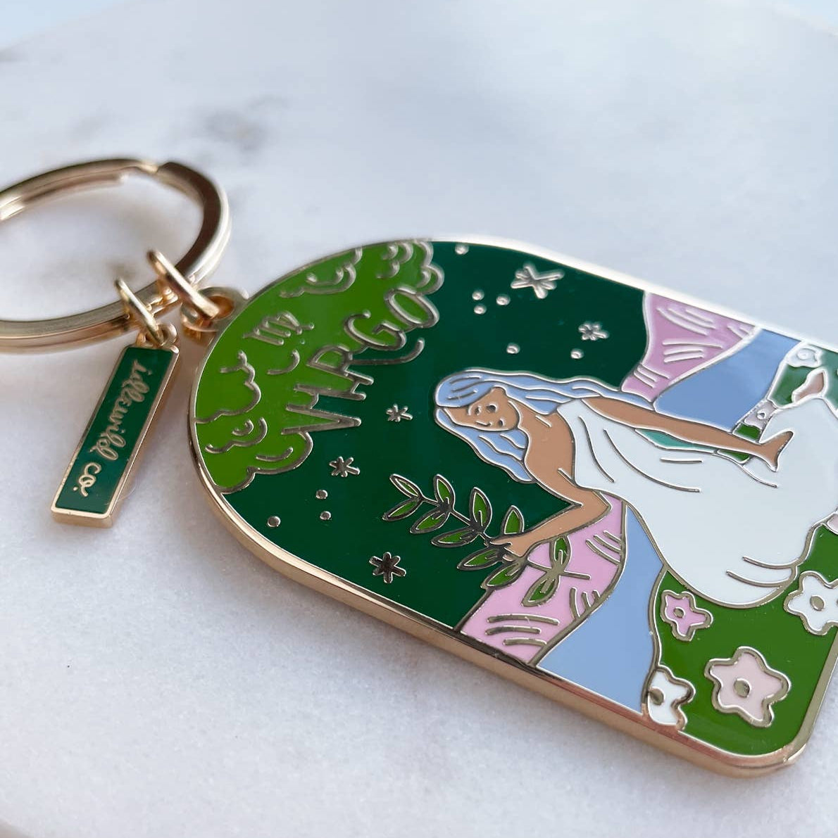 Keychain with artistic design of a woman in a garden on a white surface