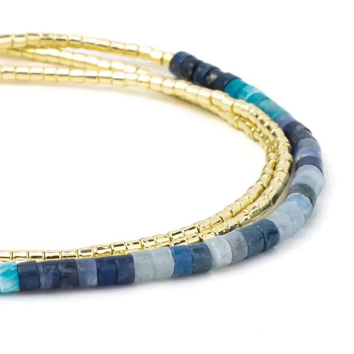 Set of beaded bracelets with gold, blue, and gray beads on a white background