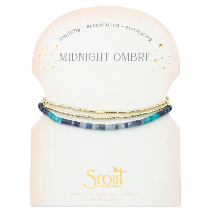 A three-strand bracelet necklace set displayed on a cream-colored card. The set includes a gold chain, a gold beaded chain, and a blue and white striped beaded chain.