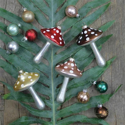 Mushroom-shaped Christmas ornaments on a leaf with a wooden background