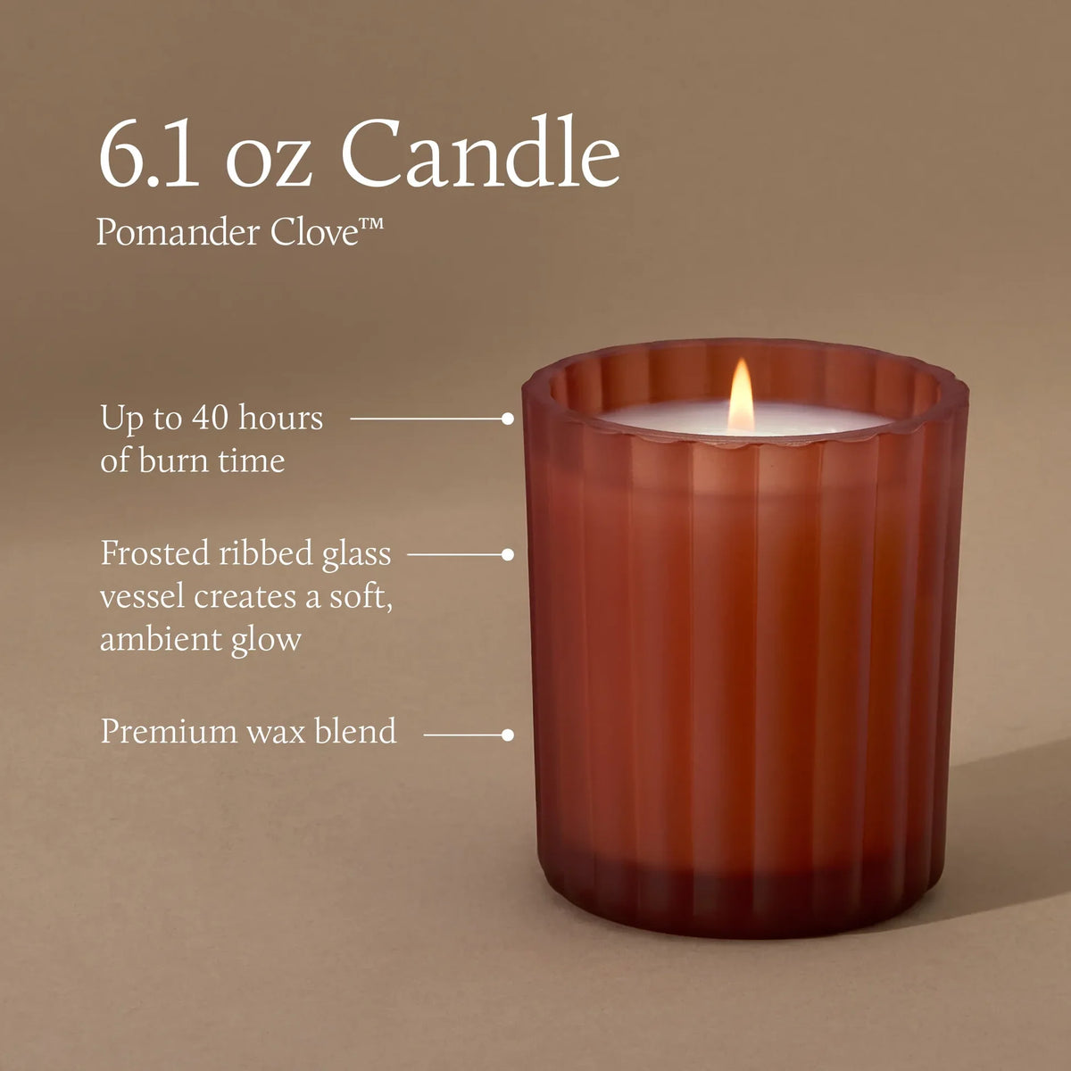 A lit 6.1 oz Pomander Clove candle in a frosted ribbed glass vessel, shown on a warm taupe background with callout text describing its burn time, glass finish, and wax blend.