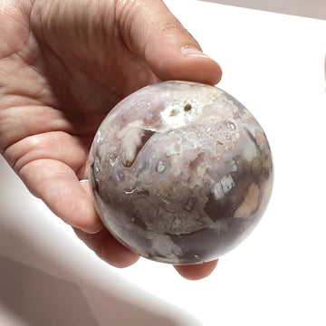 Video of hand holding a flower agate sphere
