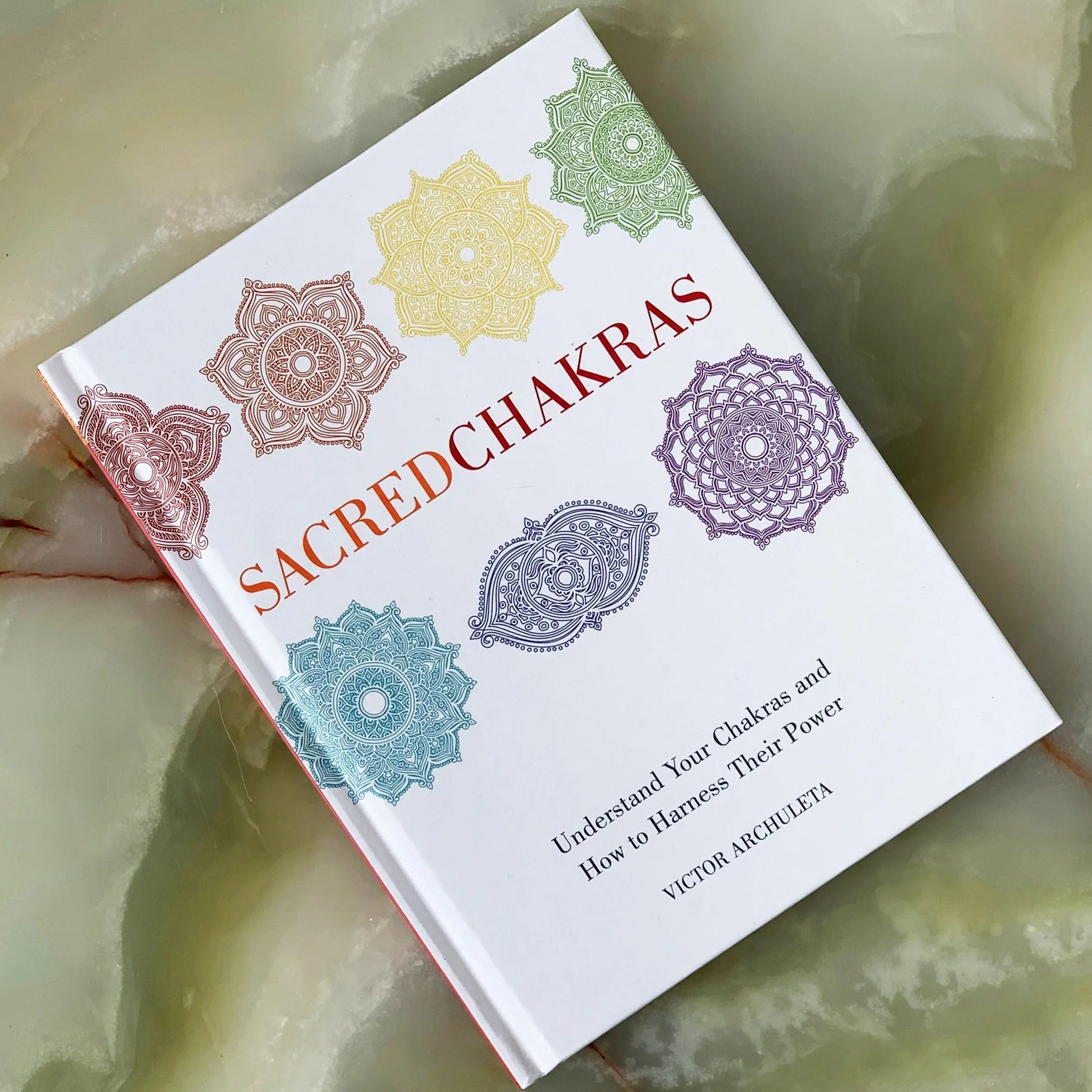 Book titled 'Sacred Chakras' on a marble surface