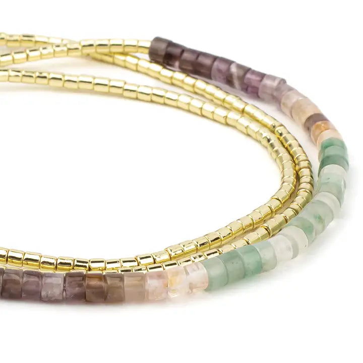 Set of beaded bracelets with gold, purple, and green beads on a white background