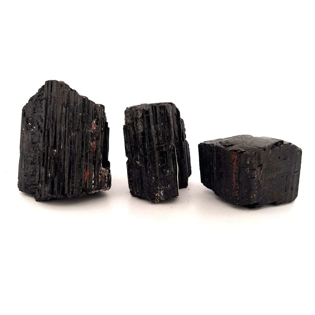 Three rough black tourmaline specimens with a layered, ribbed texture, arranged side by side on a plain white background.