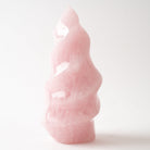 A small polished pink rose quartz stone flame sculpture with a wavy, abstract shape, photographed on a clean white background.