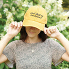Person wearing a yellow cap with 'Soul full of sunshine' text, standing outdoors with greenery in the background.