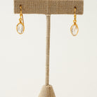 Gold herkimer diamond earrings on a beige jewelry stand against a white background