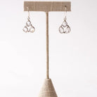 Pair of silver herkimer diamond earrings on a beige earring stand against a white background