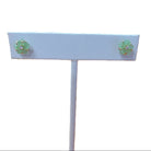 Pair of green earrings on a white earring stand with a white background