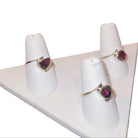 Two rings with gemstones on white mannequin stands against a white background