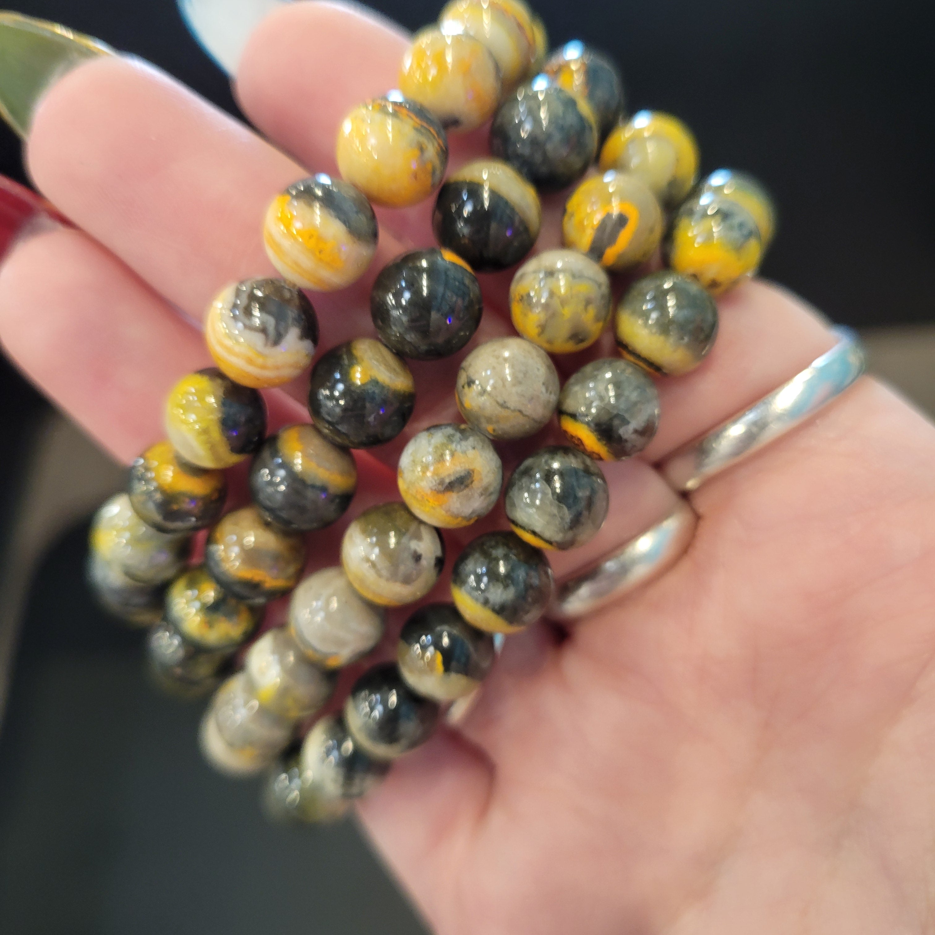 Bumble Bee Jasper bead Bracelet held in a hand with a blurred background