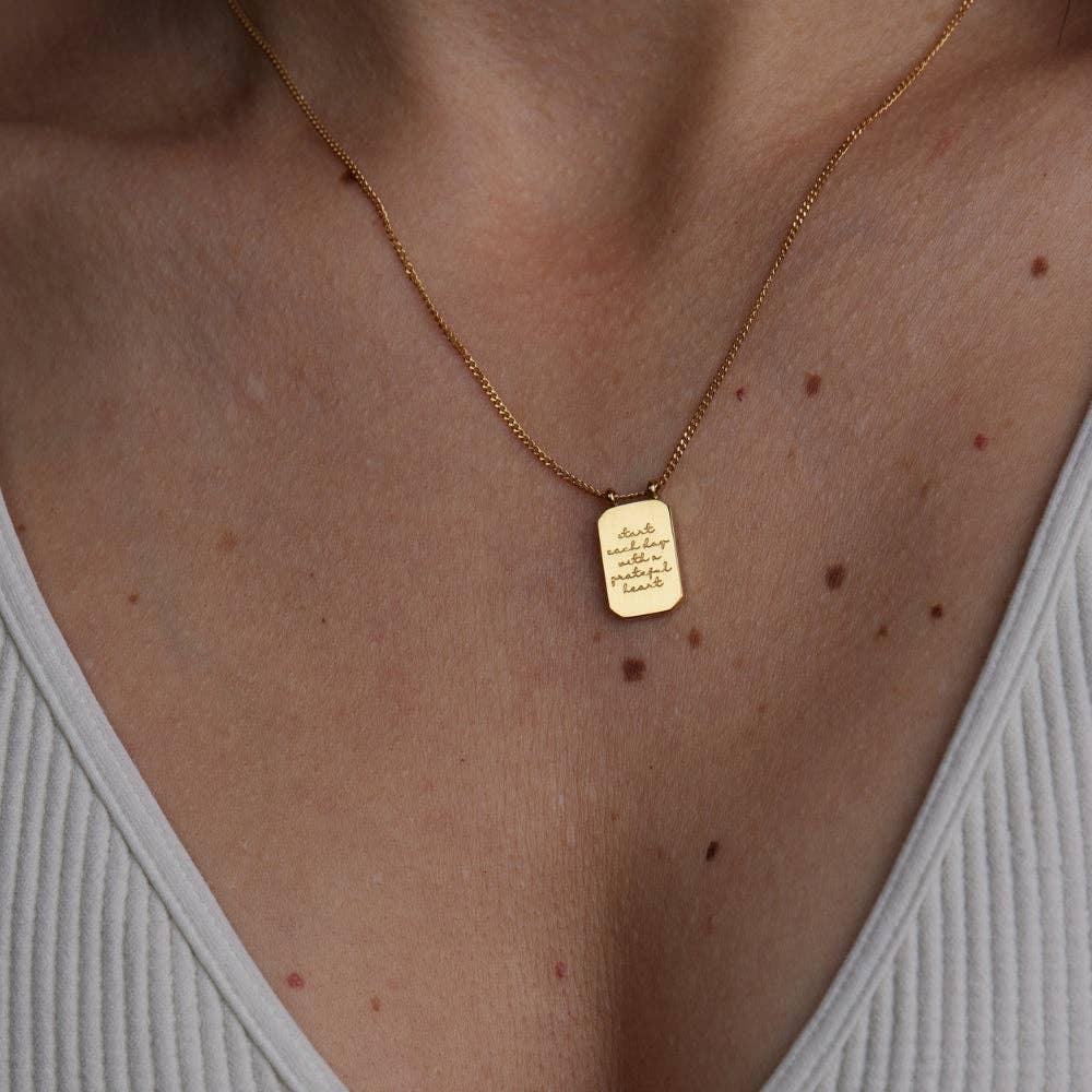 Gold necklace with a pendant on a person's neck