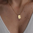 Gold necklace with a pendant on a person's neck