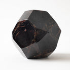 A faceted dark red garnet gemstone specimen on a clean white background.