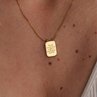 Gold necklace with a pendant on a person's neck