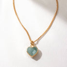 Gold necklace with a heart-shaped Aquamarine pendant on a white background
